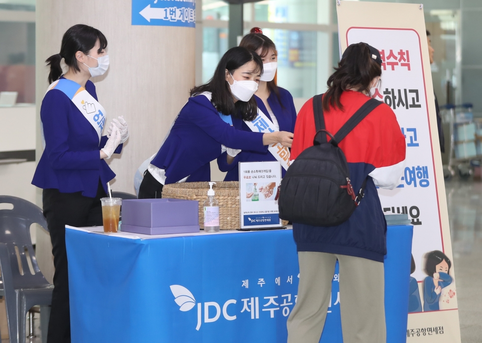 JDC 직원들이 제주국제공항에서 제주를 찾은 관광객들에게 손세정제를 나눠주고 있다.