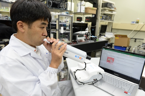 ETRI 박형주 선임연구원이 전자 코 성능 확인을 위해 숨을 불어넣는 모습