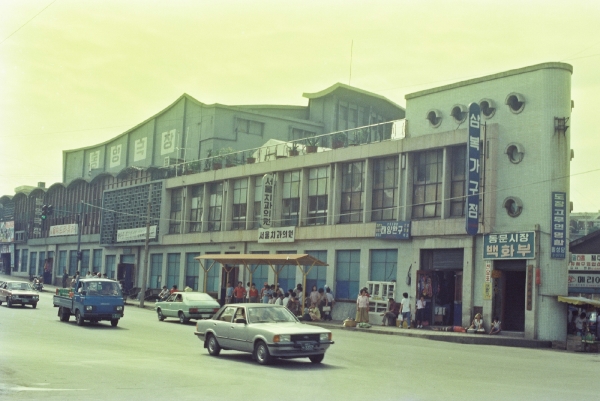 1980년대 동문시장㈜ 건물. 1965년 완공된 동문시장㈜에 동양극장이 들어선 모습. 건물 앞으로 지나가는 포니승용차가 눈길을 끌고 있다. 사진 제주시 제공.