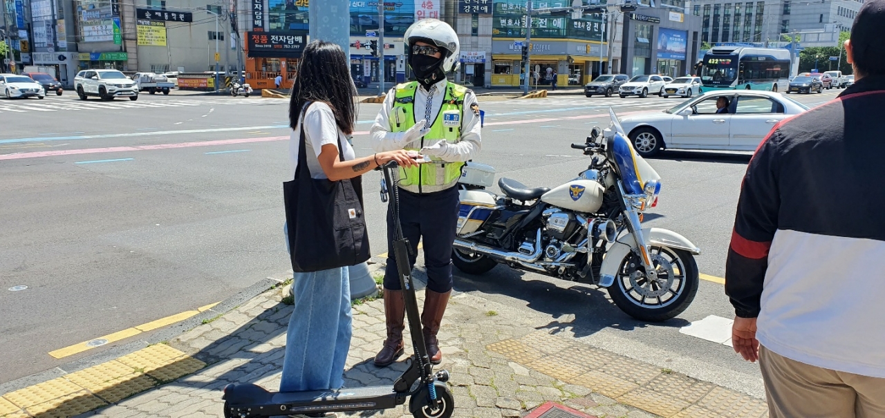 13일 제주시 구세무서 사거리에서 헬멧을 착용하지 않은 전동 킥보드 이용자에게 경찰관이 개정된 도로교통법을 안내하고 있다.