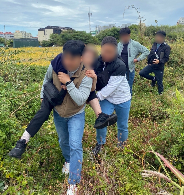 지난 20일 제주시 화북동의 한 풀숲에 쓰러져 있던 70대 여성을 발견한 경찰관이 쓰러져 있던 여성을 업고 가고 있다.